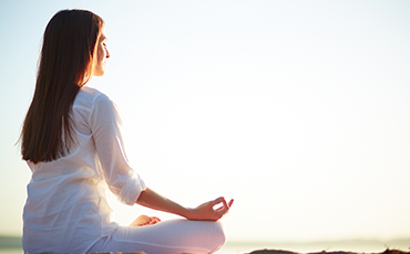 Mulher meditando em frente ao sol